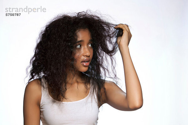 Junge Frau hält Haare auf weißem Hintergrund