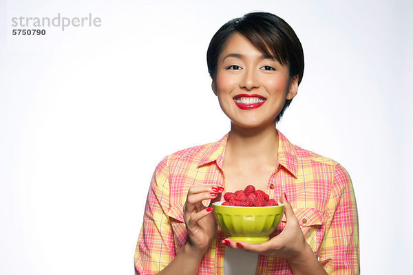 Young Woman holding Schale Himbeeren against white background