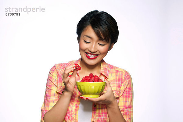 Young Woman eating Schale Himbeeren against white background