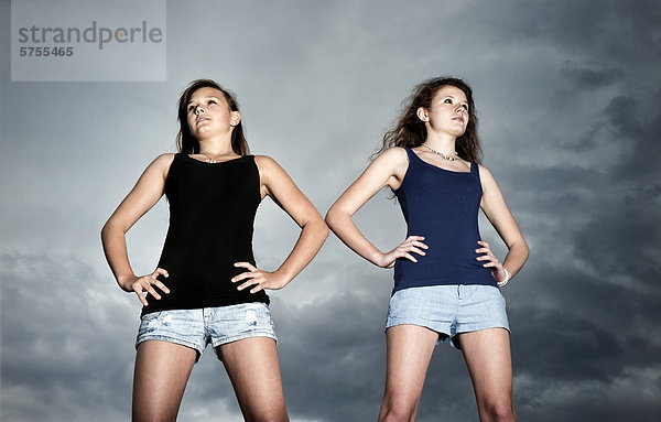 Zwei Mädchen  Teenager stehen selbstbewusst vor Gewitterwolken und blicken in die Ferne  Symbolbild  Jugend blickt in die Zukunft