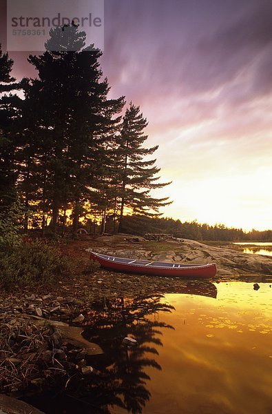 Ein Kanu  das sitzend onshore auf einem Campingplatz bei Sonnenuntergang Killarney Provincial Park  Ontario  Kanada.