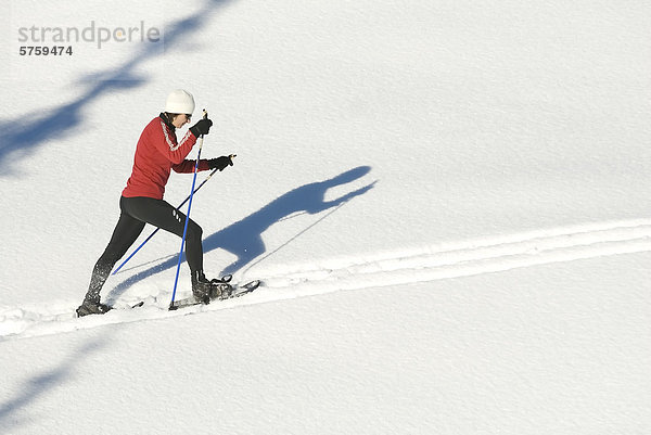 Frau mittleren Alters wirft Schatten  Schneeschuhwandern  Sun Peaks Resort  British Columbia  Kanada.