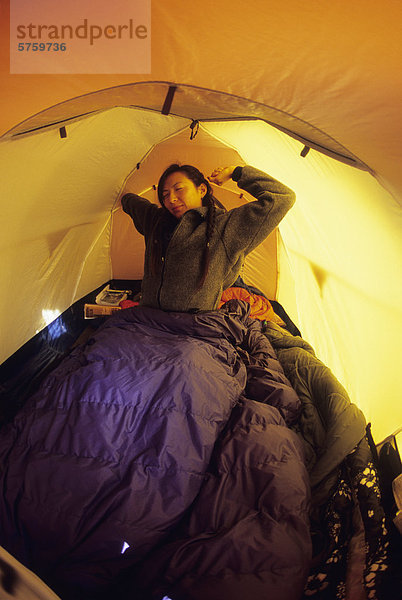Eine junge Frau wach und Dehnung in einem Zelt in Jasper  Alberta  Kanada.