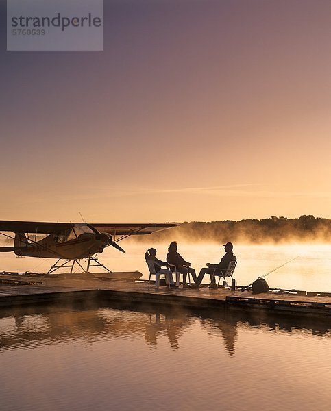 Silhouette der Familie sitzen auf Wasserflugzeug dock am Morgen  Red River in Manitoba  Kanada