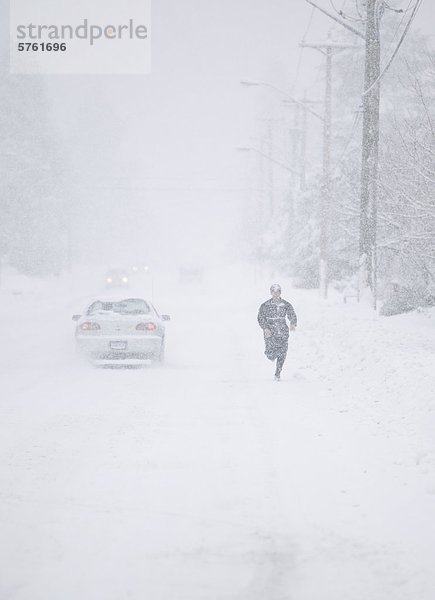 Ein einsamer Jogger konkurriert mit den Elementen und Verkehr während seiner Übung während eines Schneesturms in den Comox Valley immer. Comox  das Comox Valley  Vancouver Island  British Columbia  Kanada.