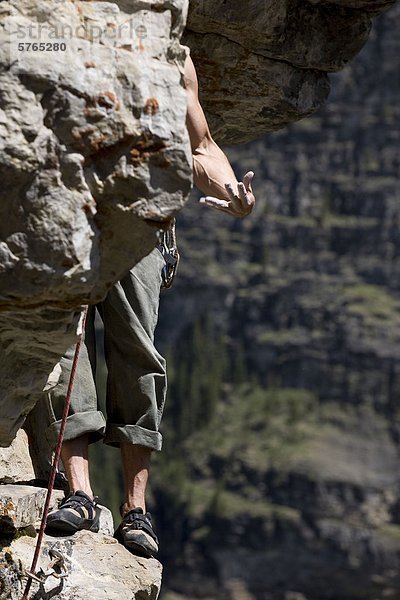 Ein Rockclimber schüttelt sich seine Unterarme beim Klettern am Lake Louise  AB