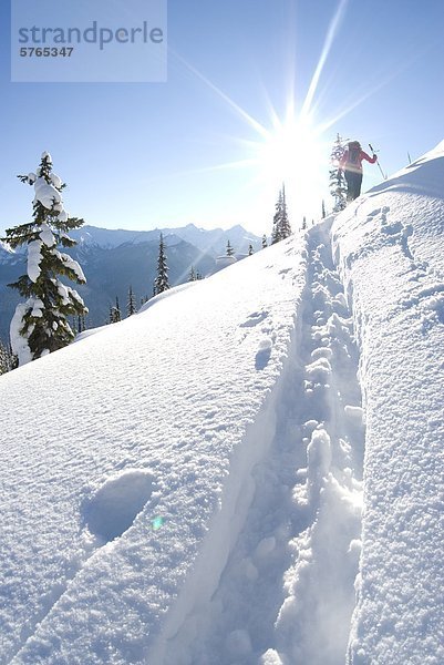 Eine junge Frau Skifahrer steigt Corbin Pass in der Nähe von Revelstoke in British Columbia