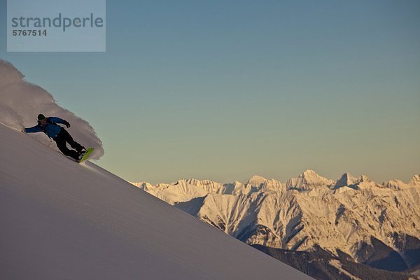 Snowboardfahrer drehen Alpenglühen