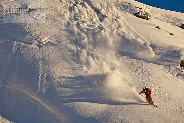 Ein männlicher Snowboarder landet eine Klippe im Powder im Backcountry  Healy Pass  Banff Nationalpark  Alberta  Kanada