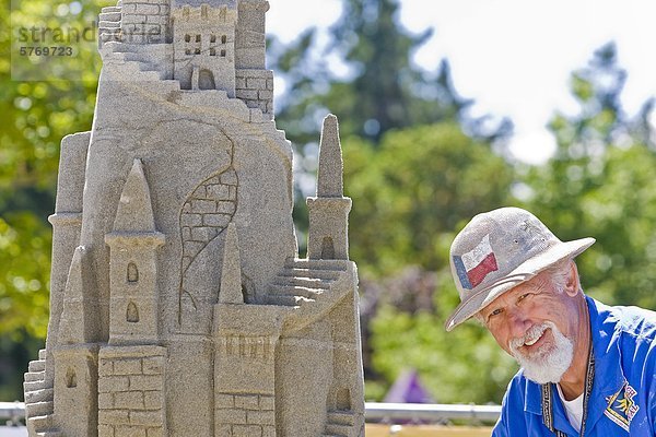 Eine Sandburg Wettbewerber mit Sandskulpturen an der jährlichen 'Parksville Beachfest' Canadian offene Sandburg Wettbewerb  Parksville  zentrale Vancouver Island  British Columbia  Kanada.