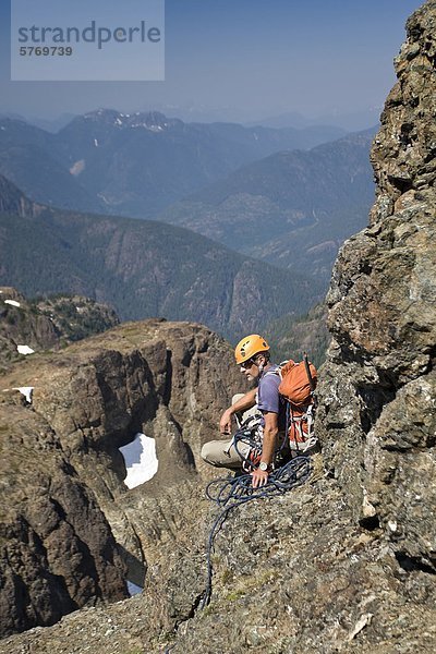 Ein Kletterer macht eine Pause und wartet auf Fellow Bergsteiger ihm aufholen  während aufsteigend Elkhorn Mountain im Strathcona Park  Vancouver Island  British Columbia  Kanada