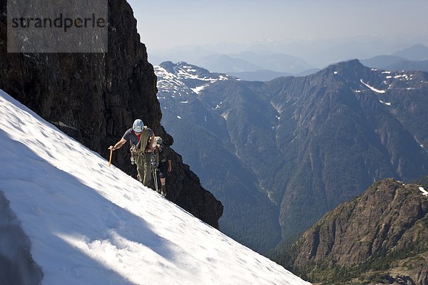 Zwei Bergsteiger aufsteigen ein Snowpatch dem Weg an die Spitze der Elkhorn Mountain im Strathcona Park  Vancouver Island  Kanada.