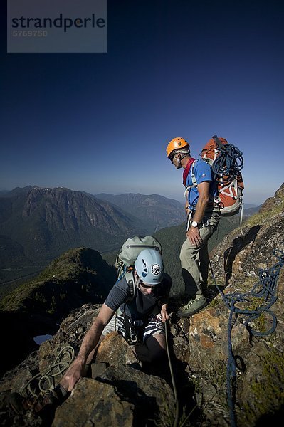 Ein Kletterer belays eine aufsteigende Kletterrose  während eine andere auf  beim Klettern Königs Peak im Strathcona Park sieht. Zentrale Vancouver Island  British Columbia  Kanada.