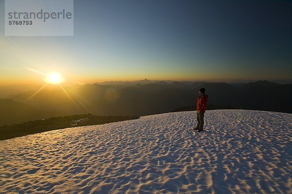 Ein einsamer Bergsteiger steht auf der Spitze des Königs Peak und genießt die letzten Strahlen der untergehenden Sonne  Strathcona Park  zentrale Vancouver Island  British Columbia  Kanada