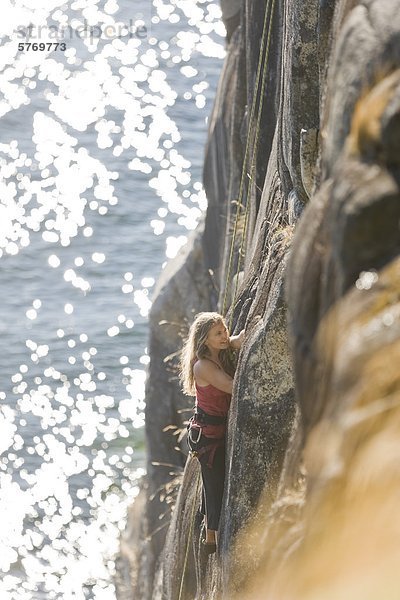 Ein weiblicher Kletterer macht ihren Weg nach oben eine der Routen Oceanside in Stillwater Bluffs südlich von Powell River auf der Sunshine Coast  British Columbia  Kanada