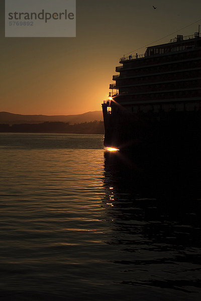 Die Sonne untergeht hinter einem Kreuzfahrtschiff angedockt am Ogden Point  Victoria  British Columbia  Kanada.