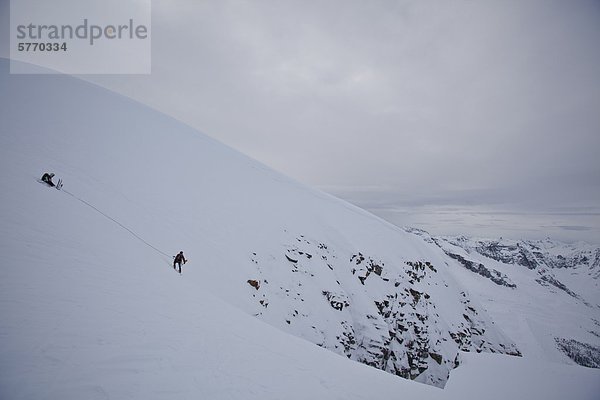 Zwei Hinterland Skifahrer Seil um die Stabilität des Hanges vor dem Abwurf in 'forever young Couloir' zu testen. Rogers Pass  Glacier Nationalpark  British Columbia  Kanada