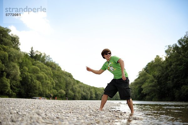 Jugendlicher lässt Steine übers Wasser springen