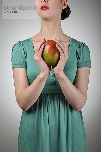 Junge Frau hält eine Mango