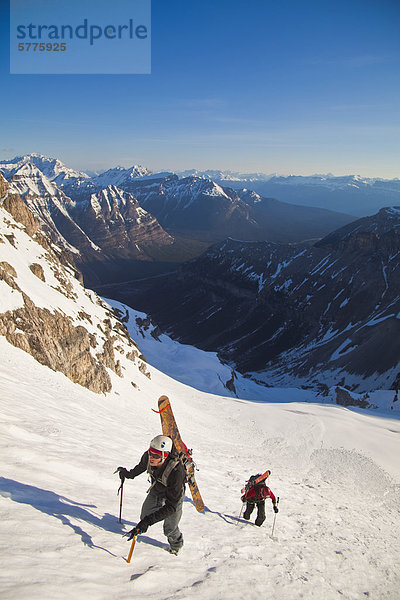 Zwei männliche Hinterland Skifahrer Bootpack bis eine steile Gesicht der Nordwand des Mt. Stanley  Kootenay Nationalpark  British Columbia  Kanada