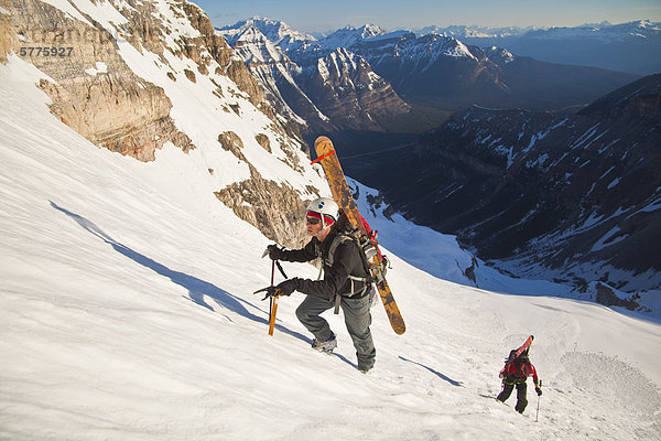 Zwei männliche Hinterland Skifahrer Bootpack bis eine steile Gesicht der Nordwand des Mt. Stanley  Kootenay Nationalpark  British Columbia  Kanada