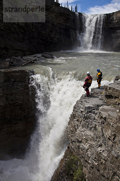 Zwei männliche Kajakfahrer scout einen großen Wasserfall des Bighorn River  Nordegg  Alberta  Kanada
