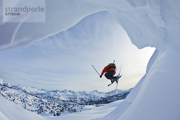 Ein junger männlicher Freeskier springt ein Gesims während Skitouren in den Monashee Berge  Britisch-Kolumbien  Kanada