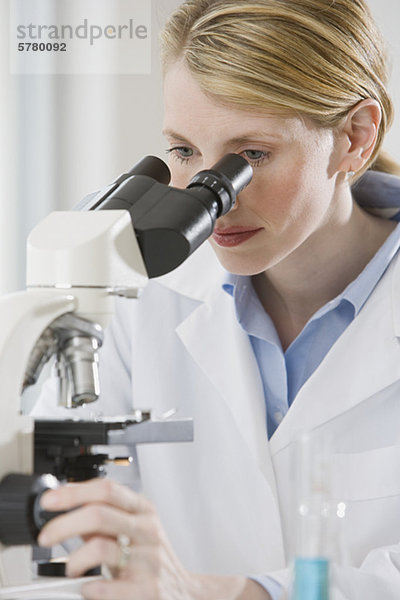 Weibliche Wissenschaftler schauen hinein Mikroskop