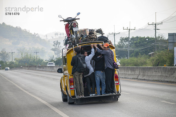 Voll beladenes Sammeltaxi oder Songthaeo oder Songthaew auf der Straße  Motorrad auf dem Dach  Nordthailand  Thailand  Asien