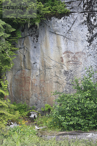 Bilder von einem Gesicht und sieben Kupferplatten  gemalt in Roter Ocker auf einer senkrechten Felswand eine 'Werbung' für einen lokalen Häuptling aus dem Tyee Gebiet des unteren Skeena River  BC wurden