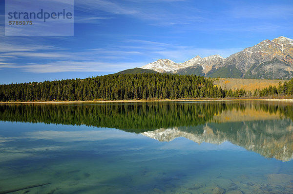 Landschaftsblick auf dem ruhigen Wasser des Sees Patrica mit Pyramid Mountain und der Küstenlinie im Hintergrund reflektiert. Dieses Bild wurde im Jasper Nationalpark  Alberta Kanada ein Herbstmorgen gefangengenommen.