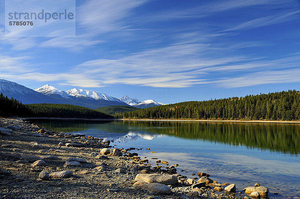 Ein Weitwinkel Landschaft Blick auf die Küste und ruhige Wasser des Sees Patrica mit schneebedeckten Rocky Mountains im Hintergrund im Jasper Nationalpark  Alberta Kanada widerspiegeln.