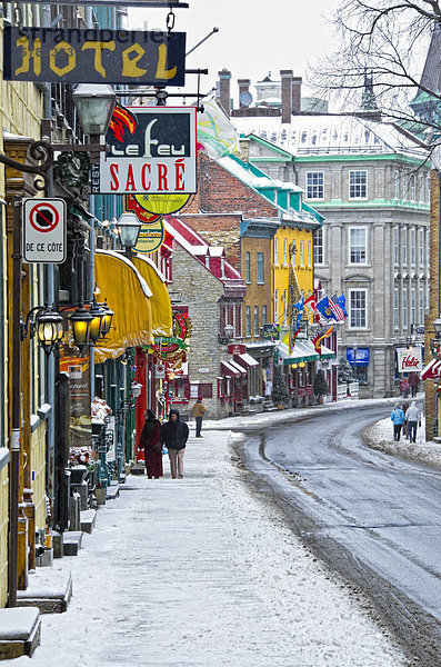 Touristen zu Fuß auf einer alten Straße mit Heritage kommerzielle Gebäude in der alten Québec im Winter bei einem Schneefall  Quebec  Kanada