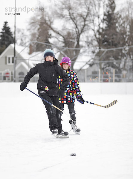 Boys playing ice hockey  on an outdoor neighborhood rink  Winnipeg  Manitoba  Canada