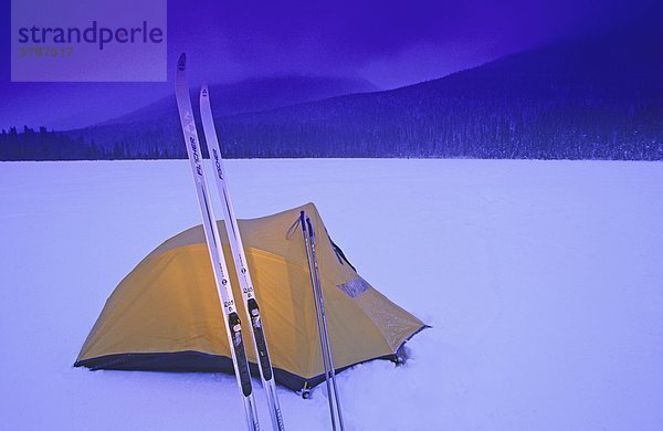 Hinterland Skifahrer Zelt glüht auf der gefrorenen Oberfläche des Indianpoint See in der Dämmerung im Winter Bowron Lakes Provincial Park  British Columbia  Kanada.