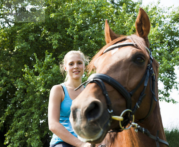 Lächelnde Teenagerin reitet auf einem Pferd