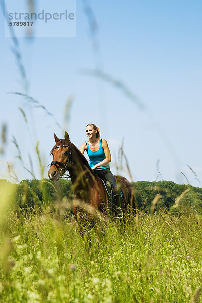 Teenagerin reitet auf einer Wiese