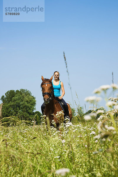 Teenagerin reitet auf einer Wiese