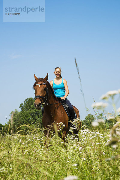 Teenagerin reitet auf einer Wiese