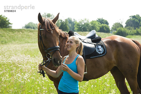 Teenagerin mit Pferd auf einer Wiese