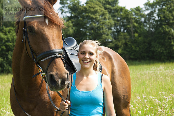 Teenagerin mit Pferd auf einer Wiese