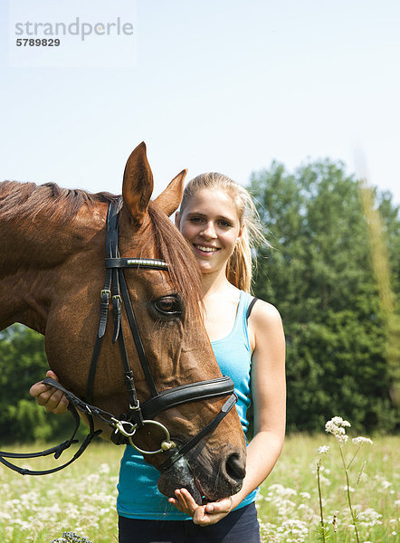 Teenagerin mit Pferd auf einer Wiese