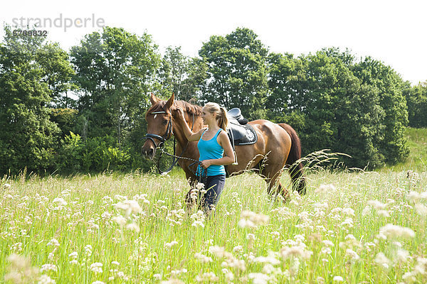 Teenagerin mit Pferd auf einer Wiese