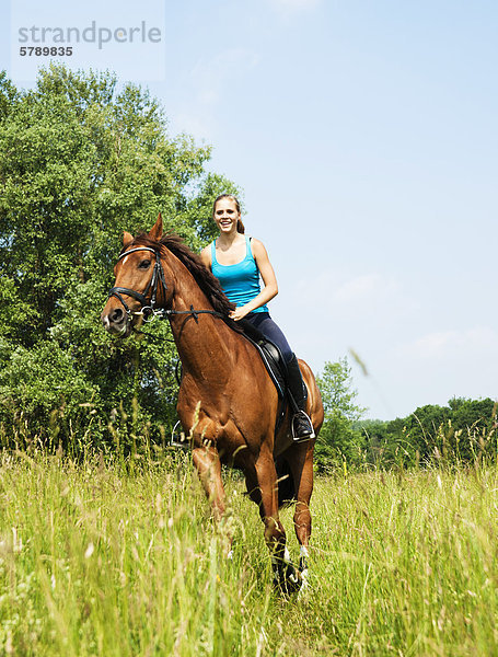 Teenagerin reitet auf einer Wiese