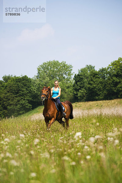 Teenagerin reitet auf einer Wiese