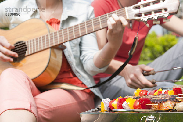 Paar grillt und spielt Gitarre