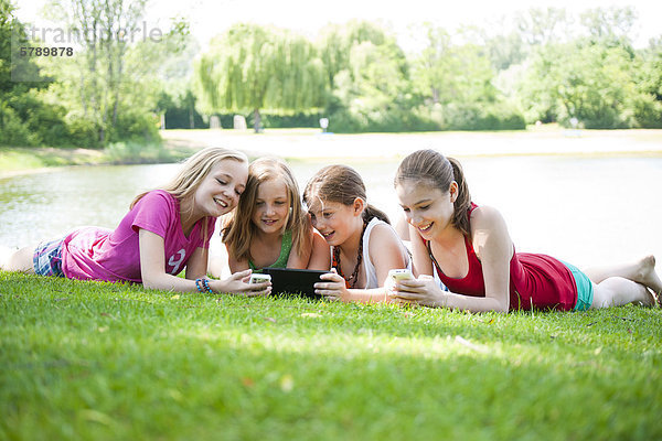 Vier Mädchen liegen auf dem Rasen an einem Badesee