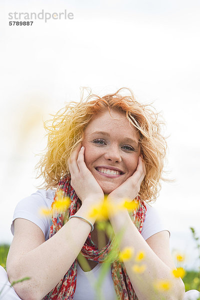 Lächelnde junge Frau auf einer Blumenwiese