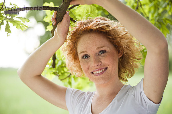 Lächelnde junge Frau an einem Baum