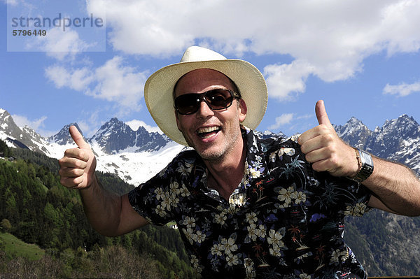 Lächelnder Mann mit Strohhut  Sonnenbrille und Daumen nach oben  in den Tiroler Bergen  Kaunertal  Tirol  Österreich  Europa
